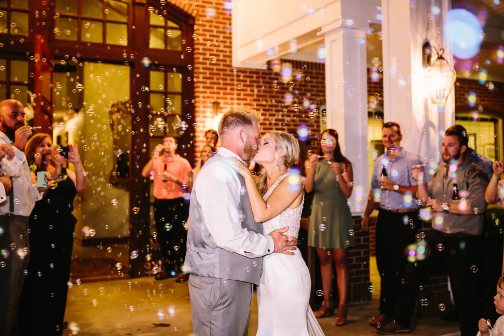 Wedding couple outdoors kissing surrounded by bubbles